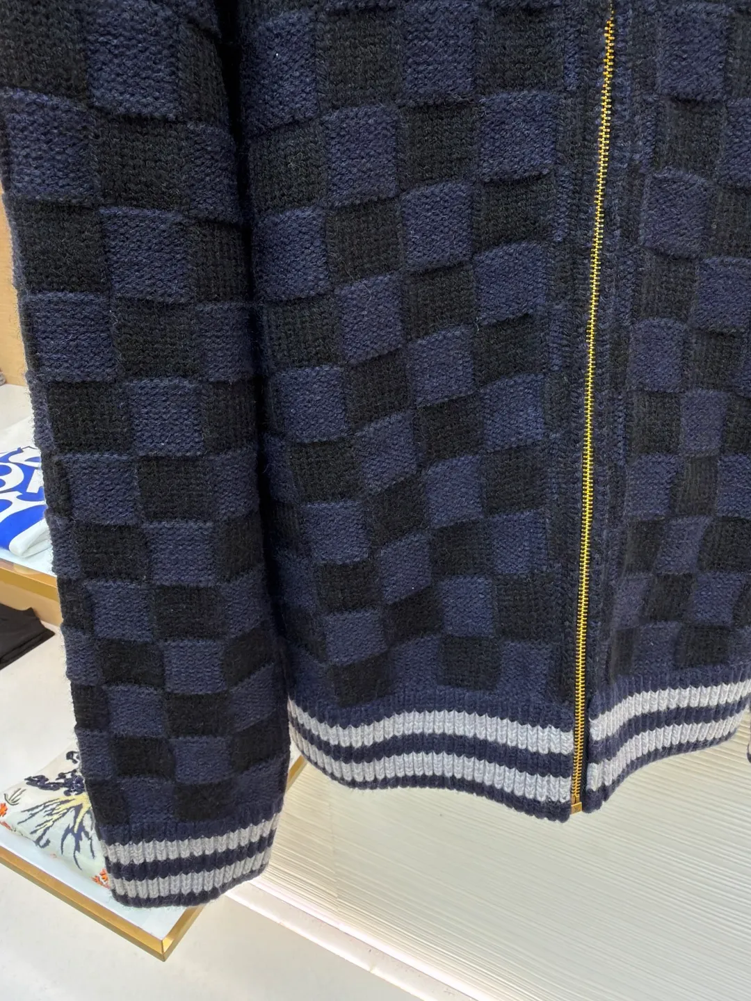 LOUIS VUITTON knitted waist contrast ribbed collar sweater ●Original version: Purchased and developed by 20433 ●Item number: 1682136-C15 ●Fabric: wool blended fabric ●Technology: knitted ●Color: black and blue ●Version: fitted version ●Weight: about 1360 grams ●Size: S-M-L-XL ●Description: This Louis Vuitton checkerboard knitted zipper jacket is made of double-ply merino wool blended yarn and is woven with a 12-needle three-dimensional knitting process on a German Stoll computerized flat knitting machine. The Damier checkerboard pattern on the body uses intarsia knitting techniques, and the layered interweaving of dark blue and black yarns creates a 3D concave and convex texture. There is no printed patchwork process, and the pattern and the body are integrated for a more textured look. The neckline is designed with contrasting ribbed lapels, and built-in spandex elastic yarn improves resilience; the metal zipper is made of gold-plated brass, and the teeth are precision polished. The zipper track and the seam of the body are sewn with overlock stitching, and the stitch length is controlled within 0.2cm. The contrasting ribbed edges on the cuffs and hem are pre-shrunk and hand-shaped and ironed, making the garment crisp and less likely to loosen after long-wearing. Every detail demonstrates the brand's strict standards of high-end knitting technology. The overall wiring is straight and delicate, the fabric is comfortable and soft, and the color is consistent without color difference. It can be matched with the same style to create a fashionable look and control various occasions. Customized accessories, complete with three standards, same style for men and women!